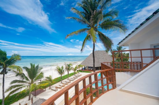 a deck with palm trees and a body of water in the background