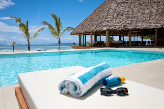 a pool with a lounge chair and a table with a white cloth on it and a straw umbrella
