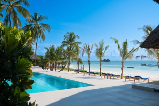 a pool with palm trees and a beach with blue water