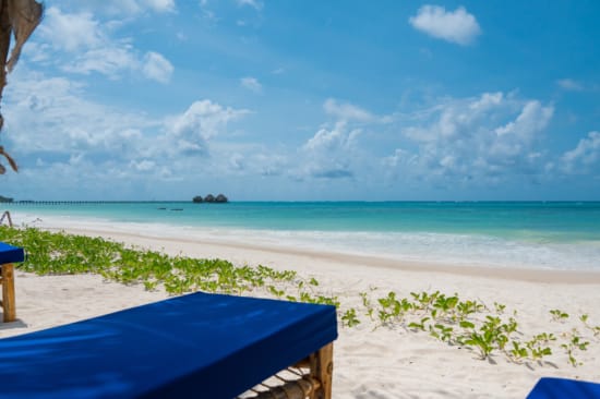 a beach with a blue sky and clouds