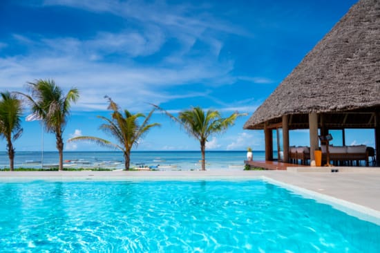 a pool with a hut and palm trees by it