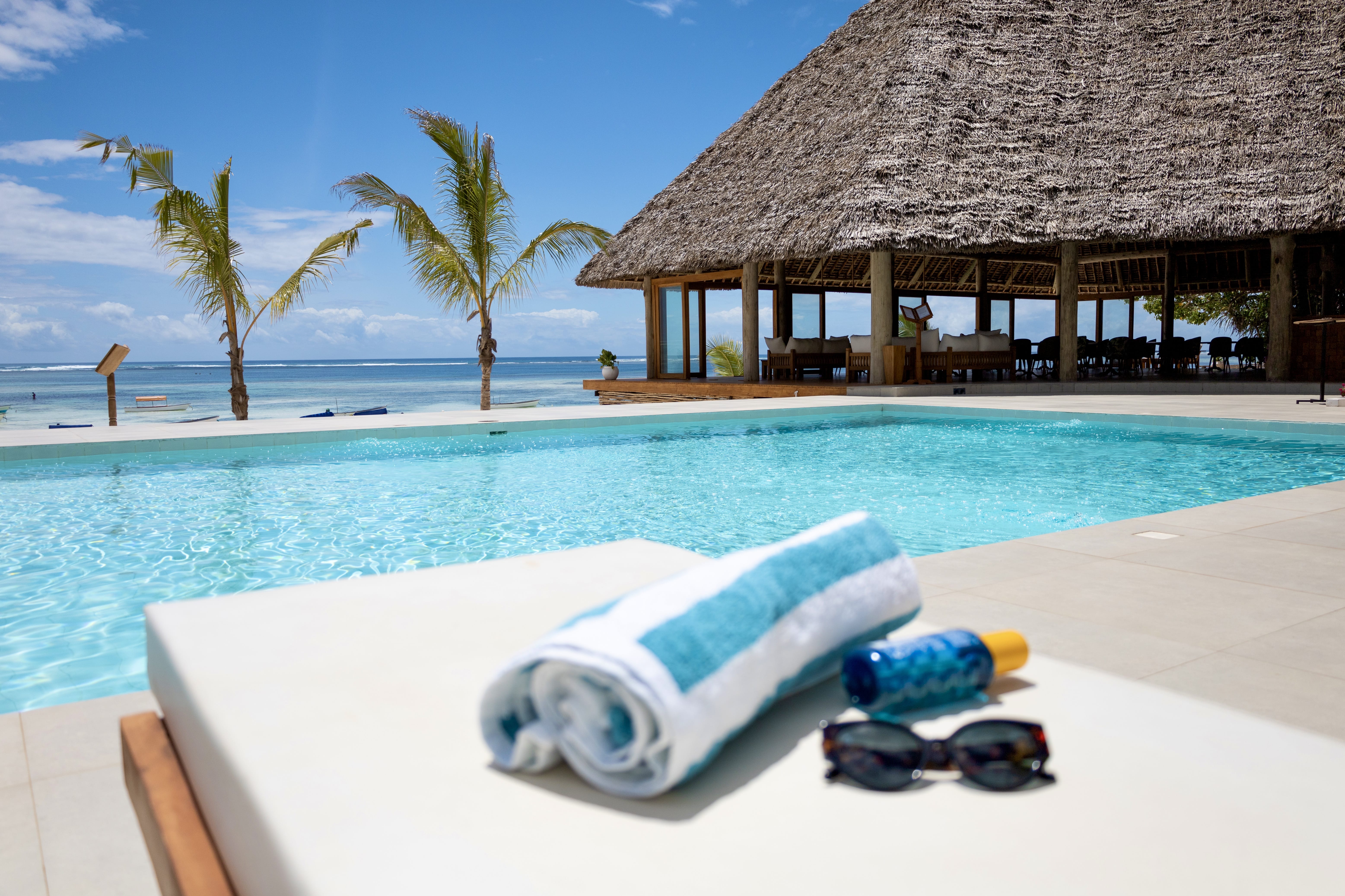 a pool with a lounge chair and a table with a white cloth on it and a straw umbrella