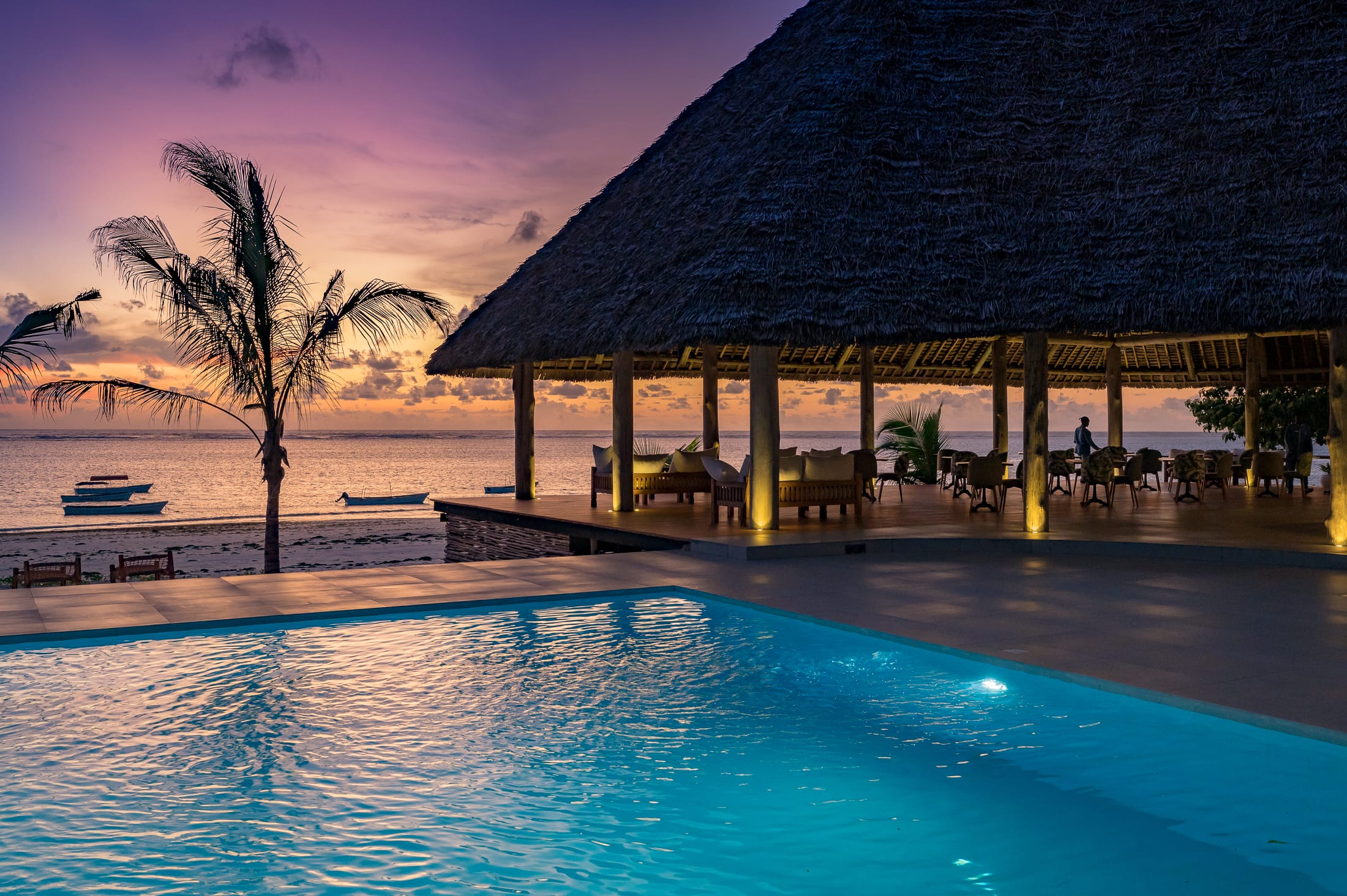 a pool with a hut in the background