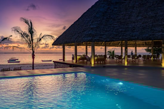 a pool with a hut in the background