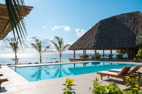 a pool with a hut and chairs by it