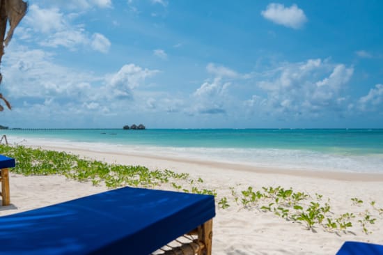 a beach with a blue sky and clouds