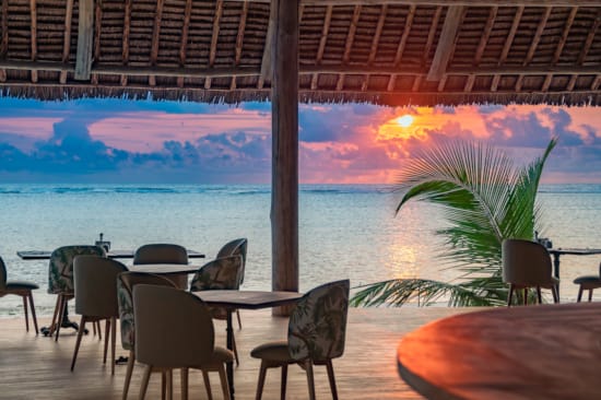 a group of tables and chairs next to a body of water