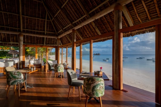a room with tables and chairs and a view of the ocean