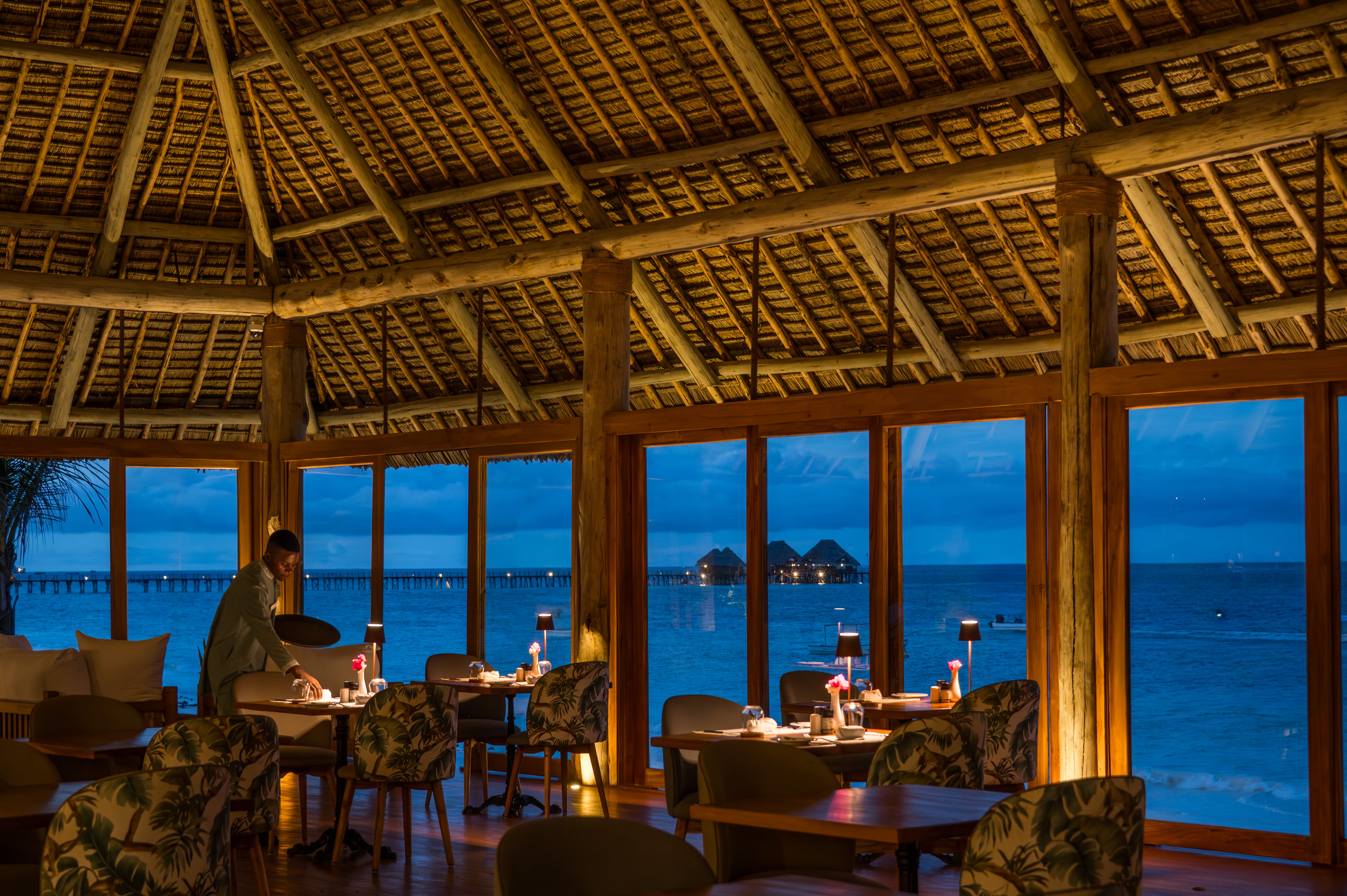 a room with a view of the ocean and a person sitting at a table