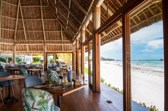 a room with tables and chairs and a view of the ocean