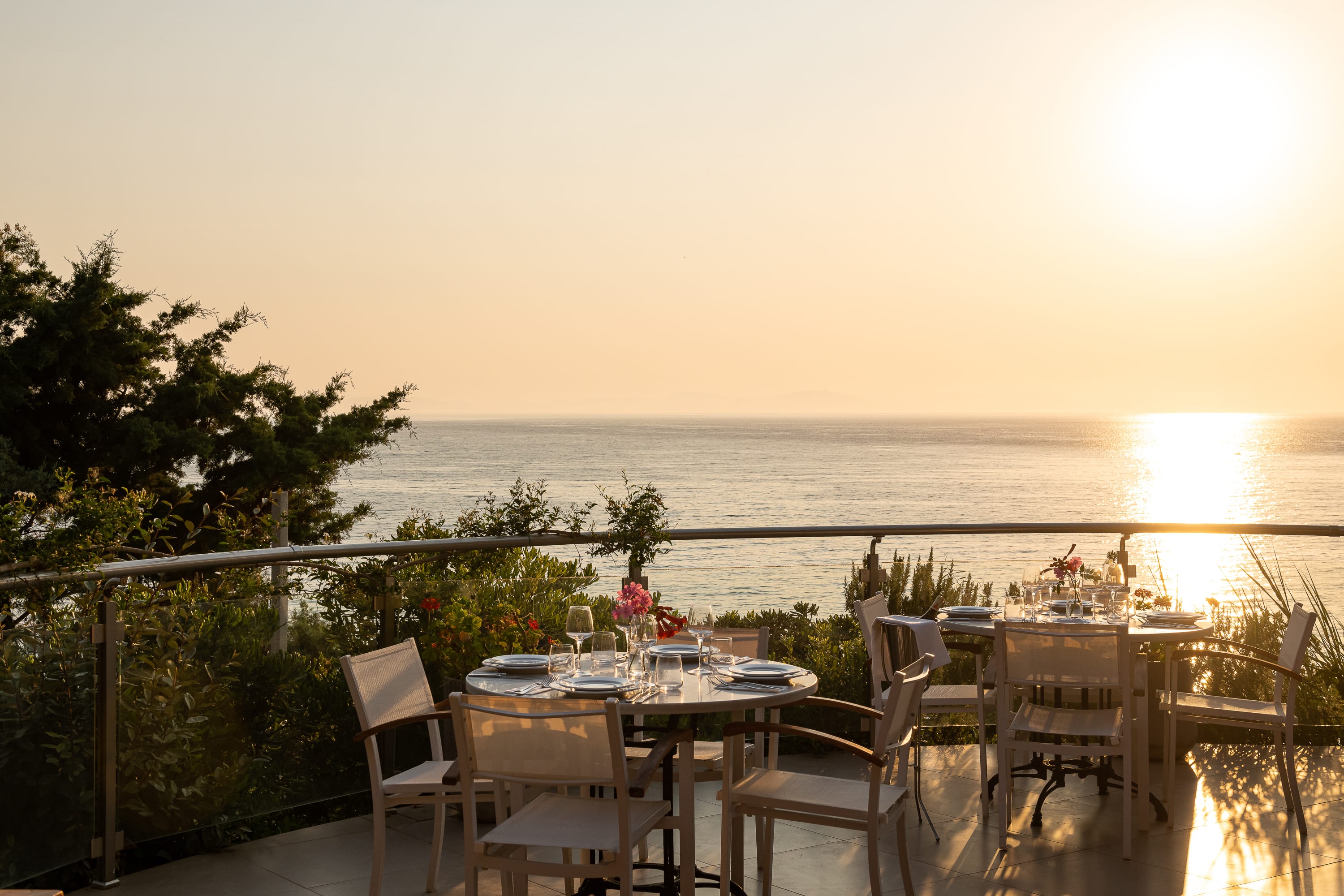 a table set with chairs on a balcony overlooking the ocean