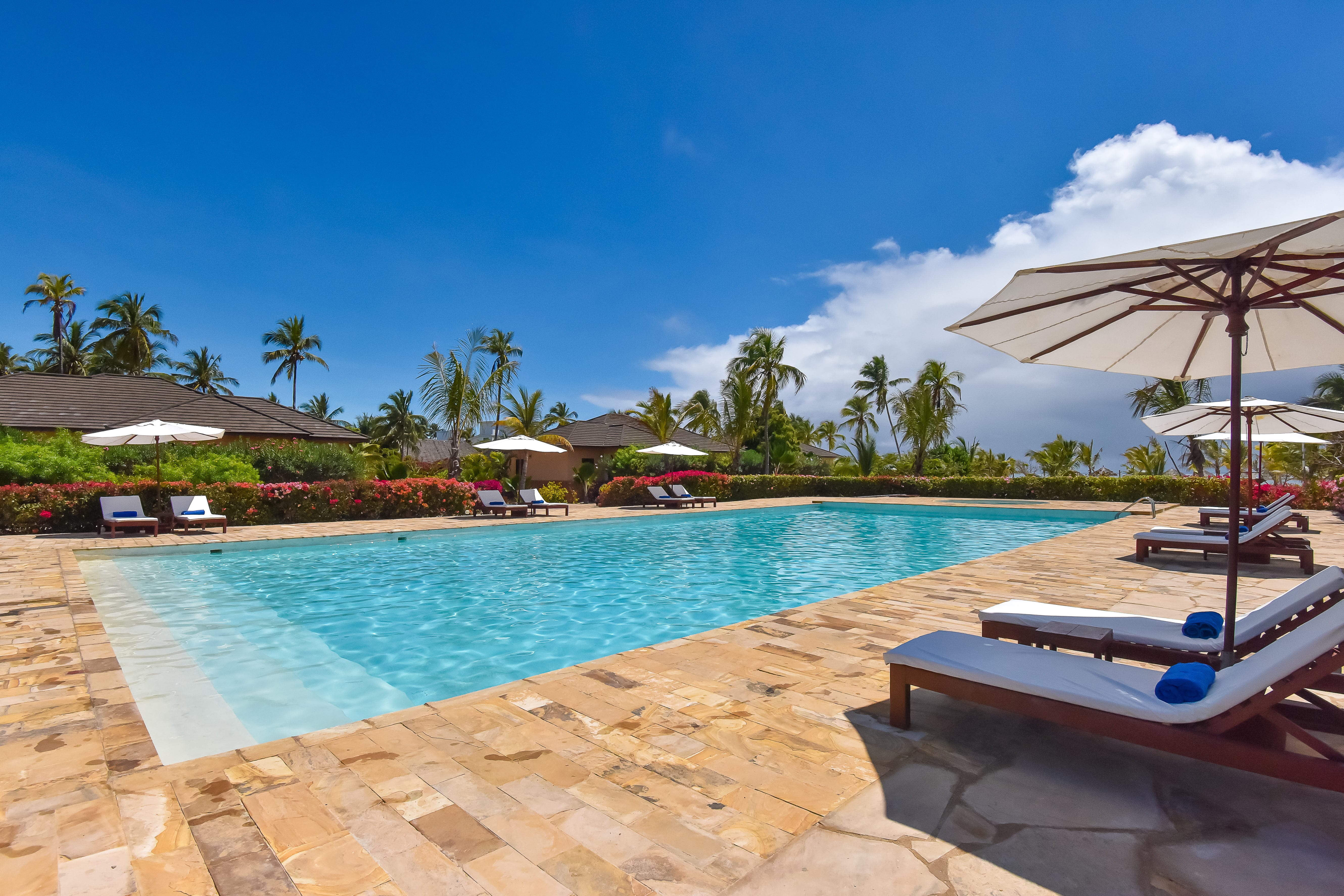a pool with lounge chairs and umbrellas by it