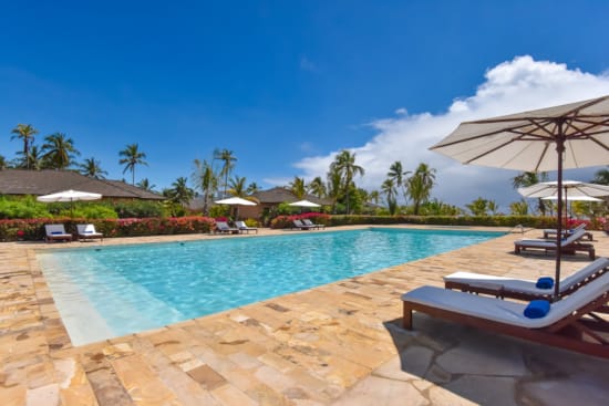a pool with lounge chairs and umbrellas by it
