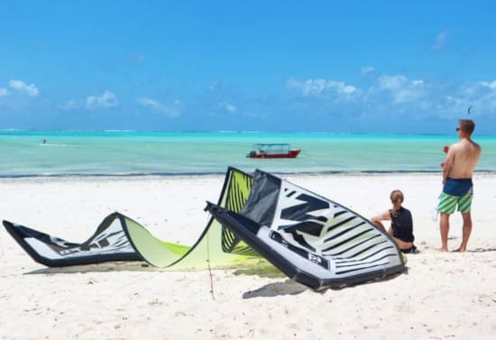 a couple of men on a beach with a kite