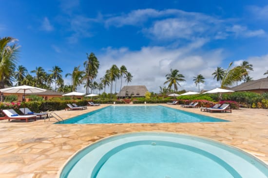 a pool with lounge chairs and umbrellas on a beach