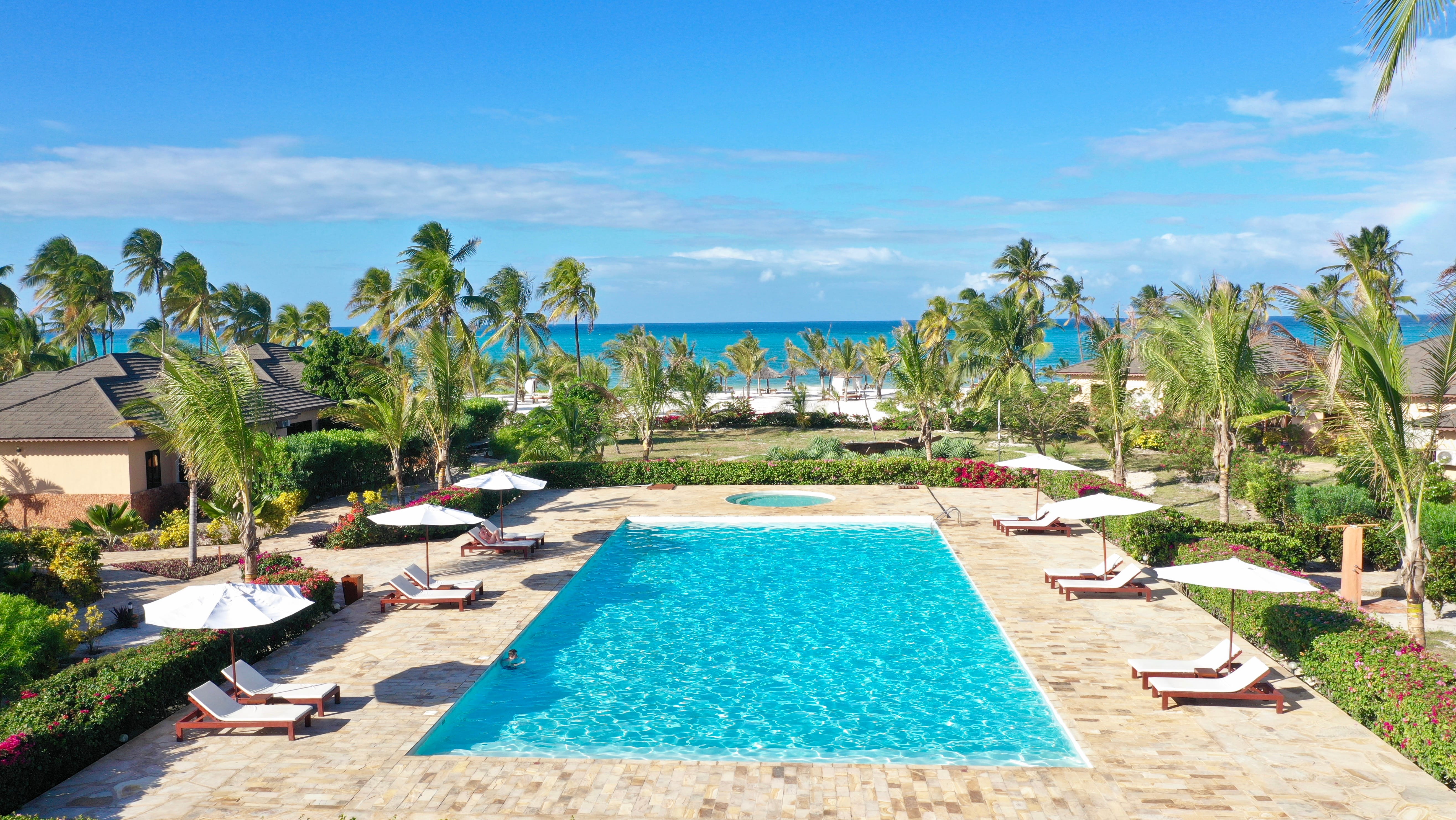 a pool surrounded by lounge chairs and umbrellas on a beach