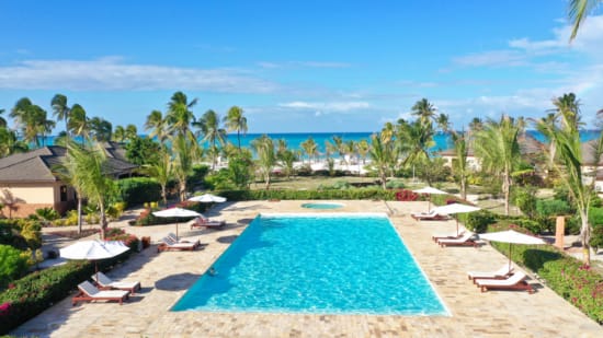 a pool surrounded by lounge chairs and umbrellas on a beach