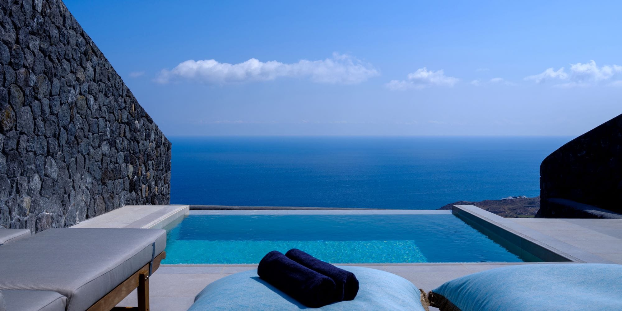 a pool with a rock wall and a blue sky