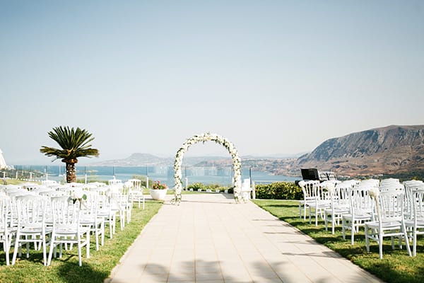 a long white pathway with white chairs and a ferris wheel in the background