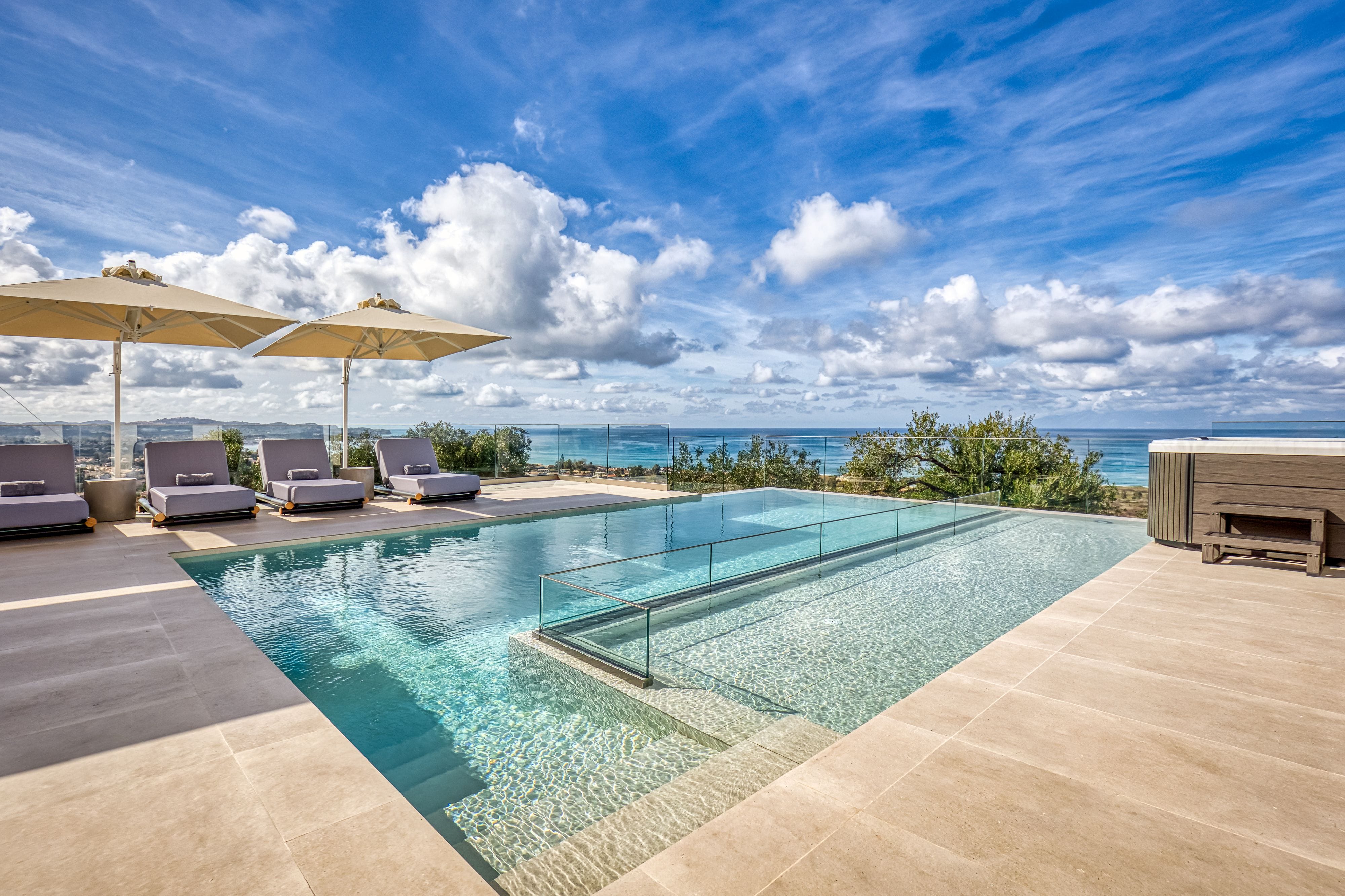 a pool with chairs and umbrellas by a beach