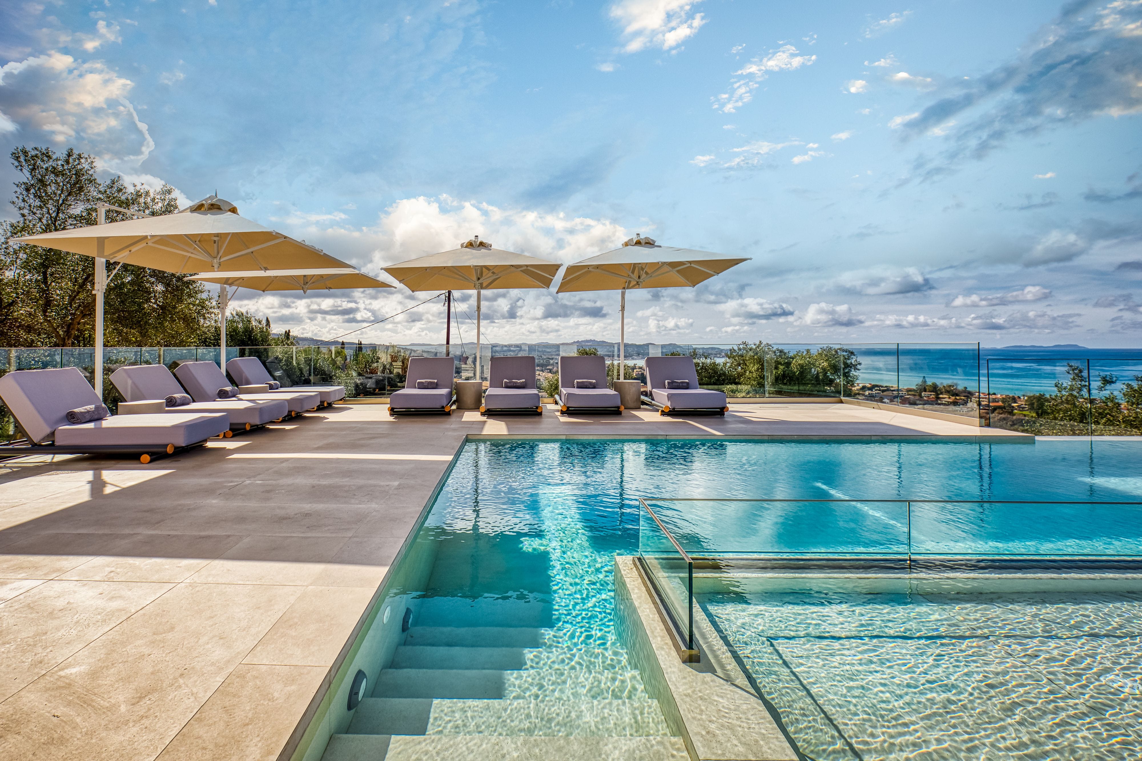 a pool with lounge chairs and umbrellas by a beach