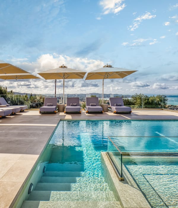a pool with lounge chairs and umbrellas by a beach