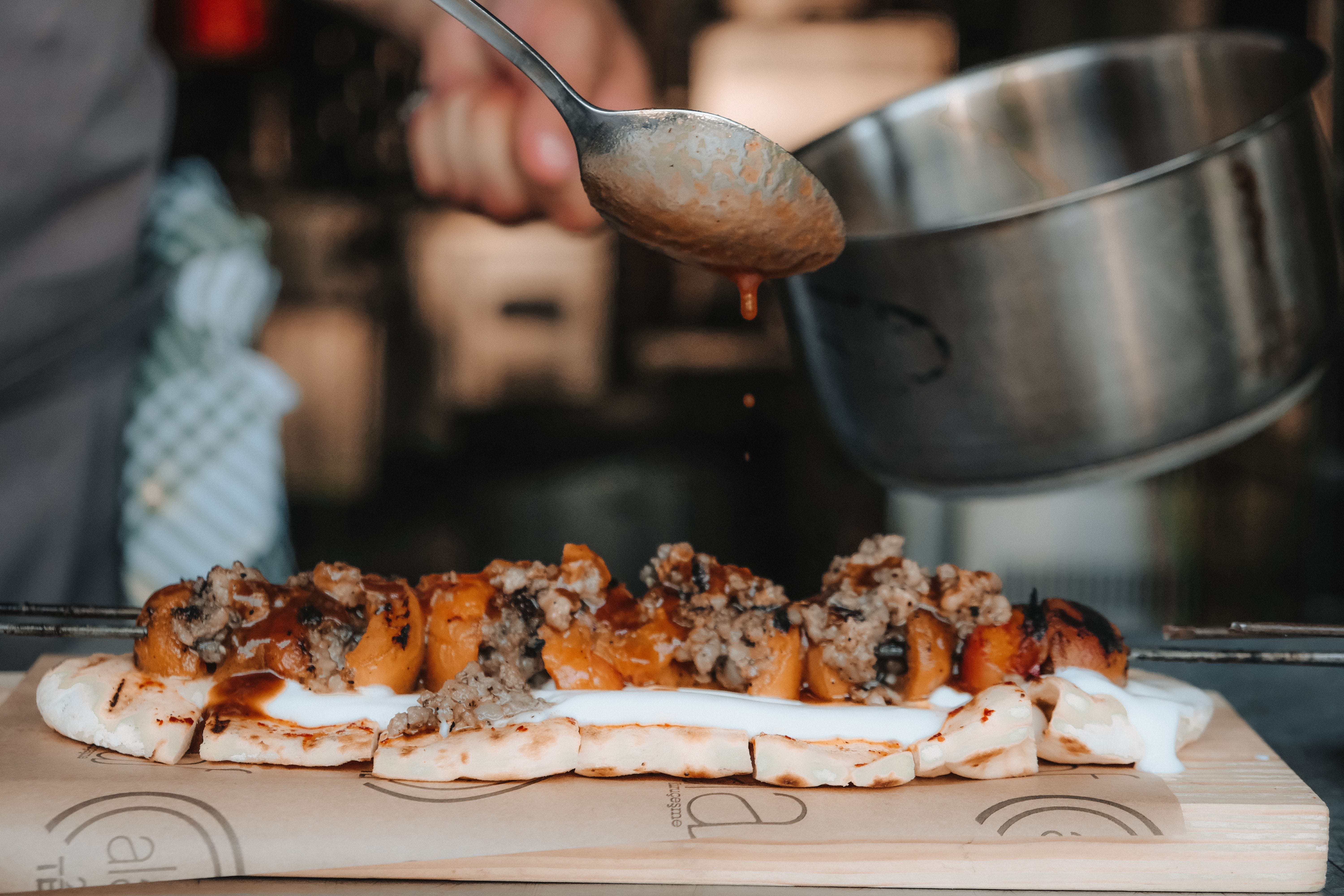 a person pouring sauce onto a food