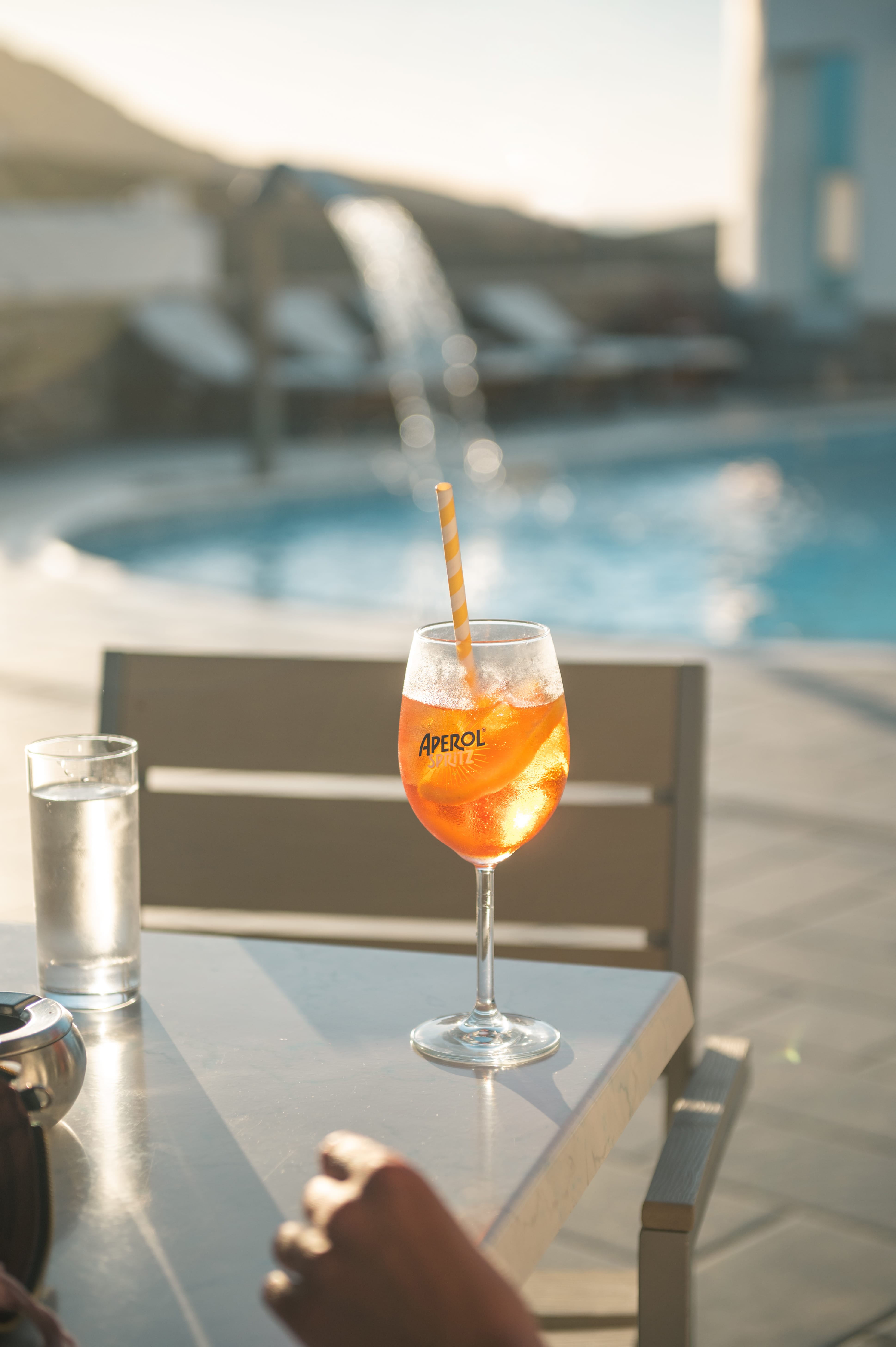 a glass of orange drink on a table by a pool