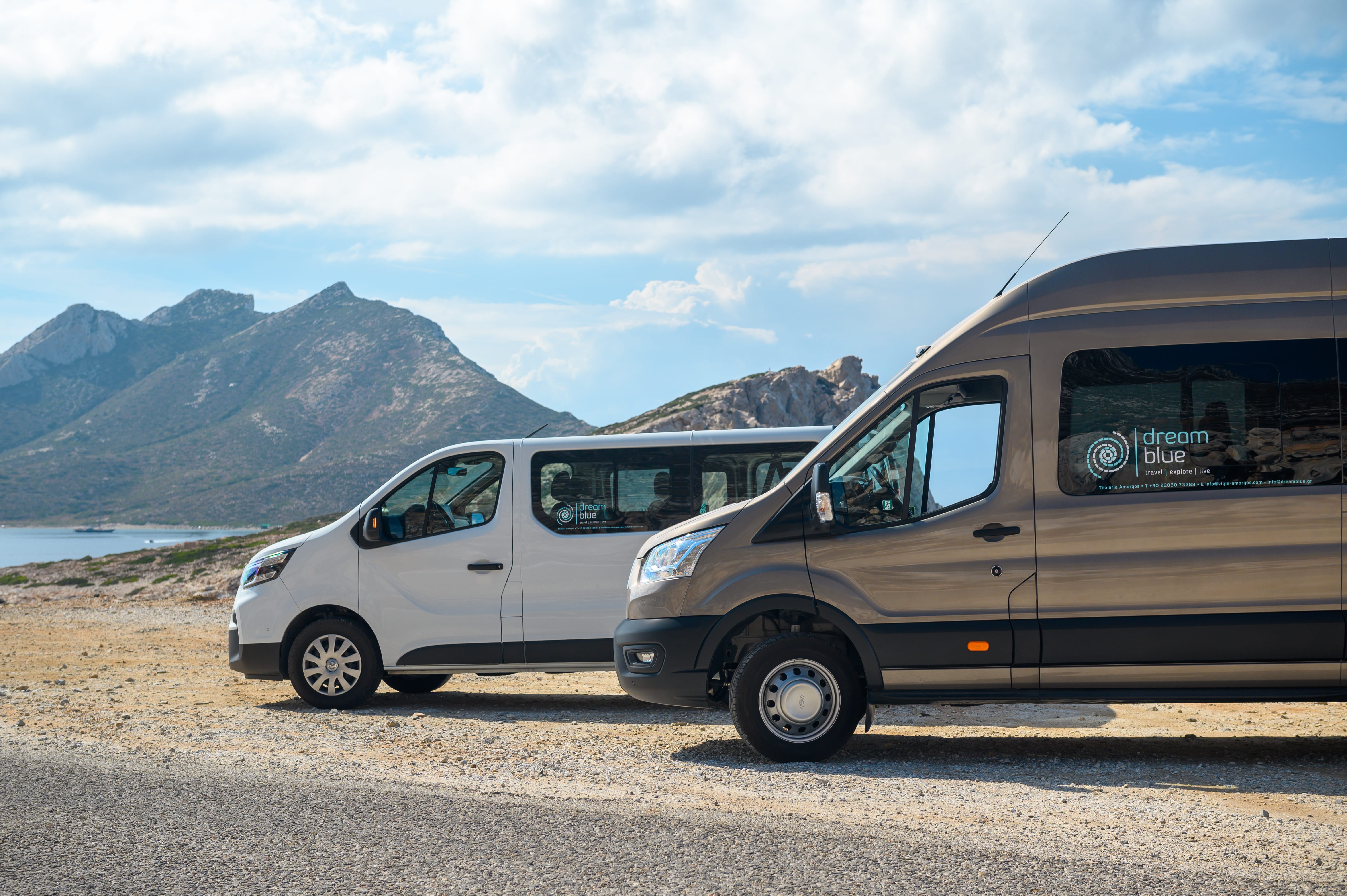 a couple of vans parked on a road by a body of water