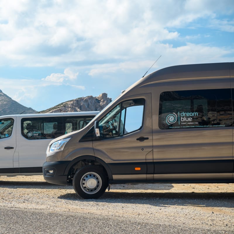a couple of vans parked on a road by a body of water