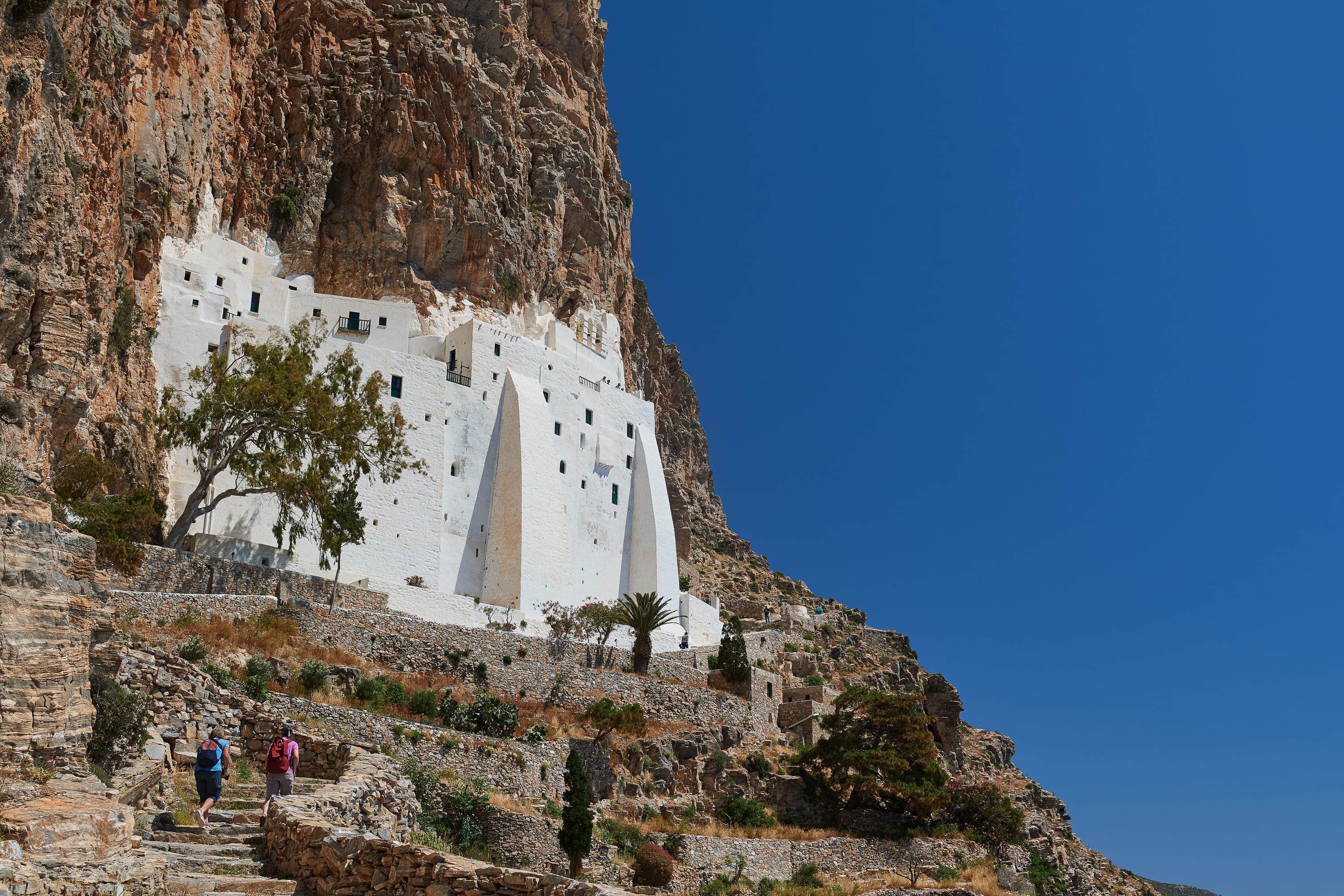 a white building on a cliff with Amorgos in the background