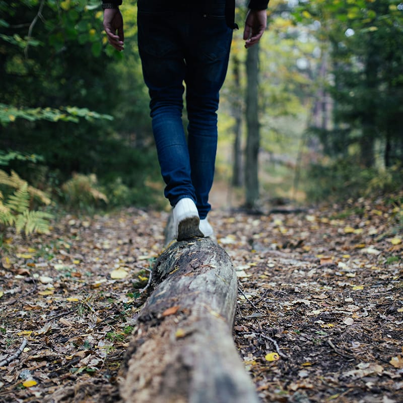 a person's legs and feet on a tree stump