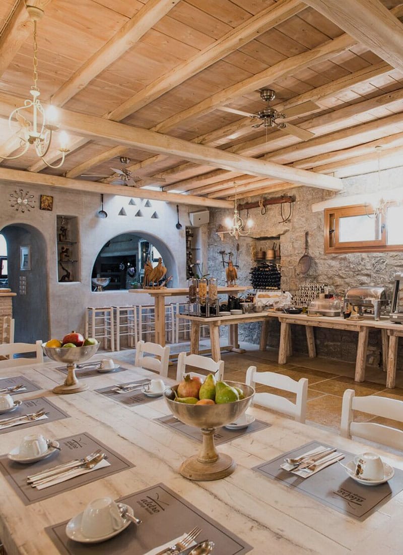 a large kitchen with a large chandelier and a table with a bowl of fruit on it