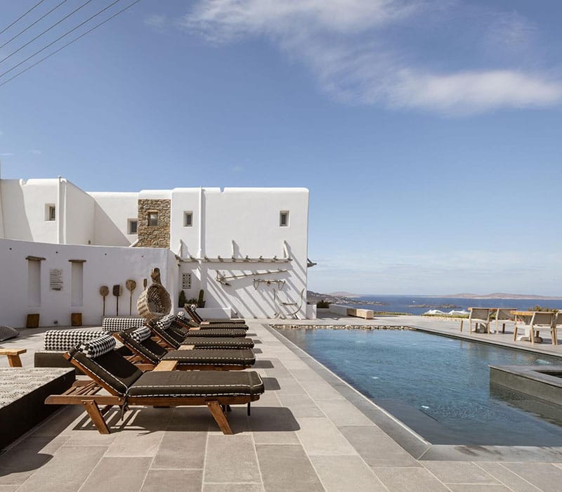 a pool and lounge chairs by a building with a blue sky