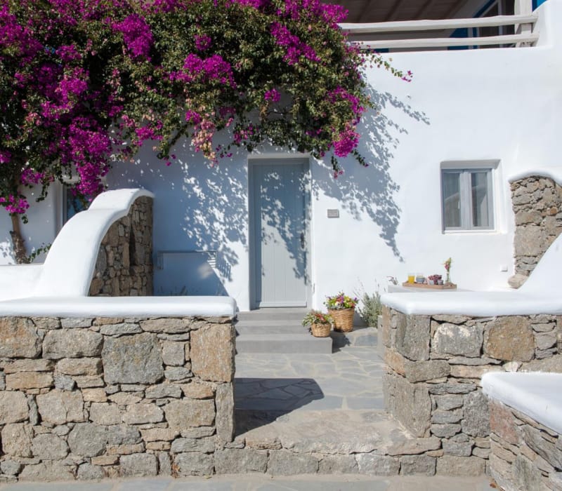 a white chair in front of a stone wall with flowers on it