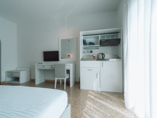 a room with a bed desk and a television