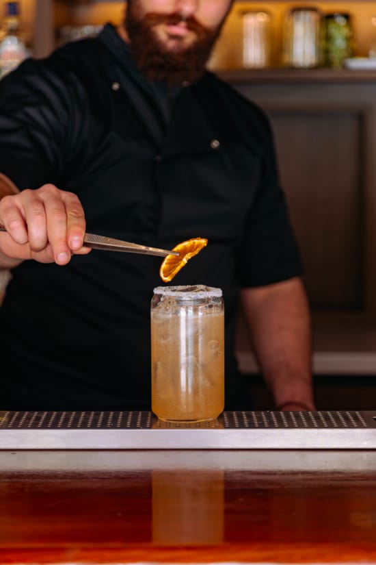 a person holding a tweezers over a glass of liquid
