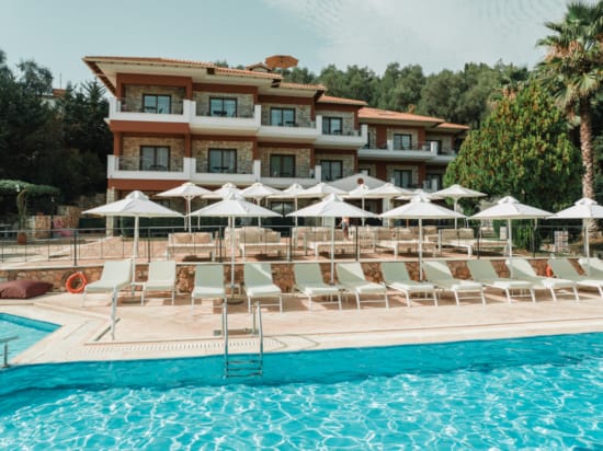 a pool with umbrellas and chairs by a building
