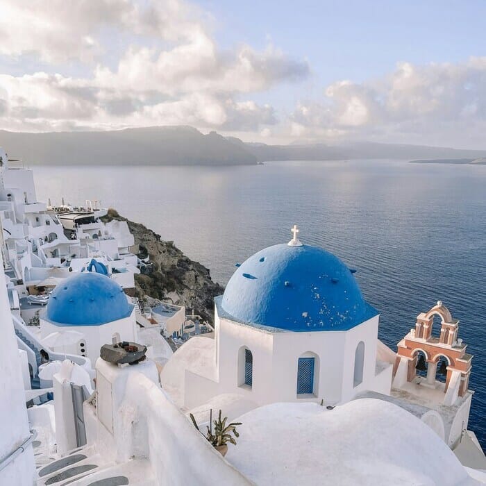 a white building with blue domes and a blue dome on a rocky hill