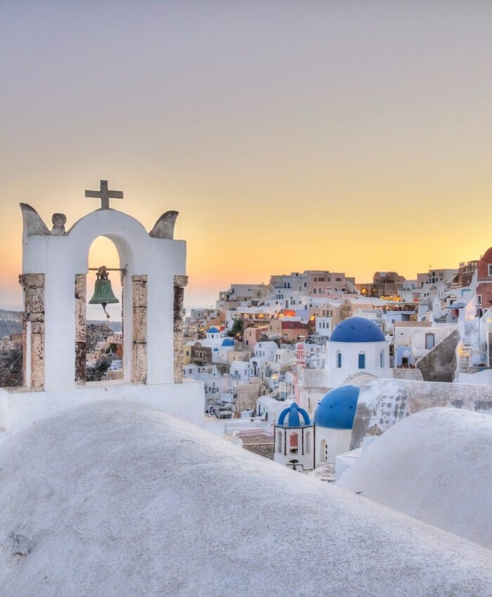 a group of white buildings with blue domes and crosses in the snow