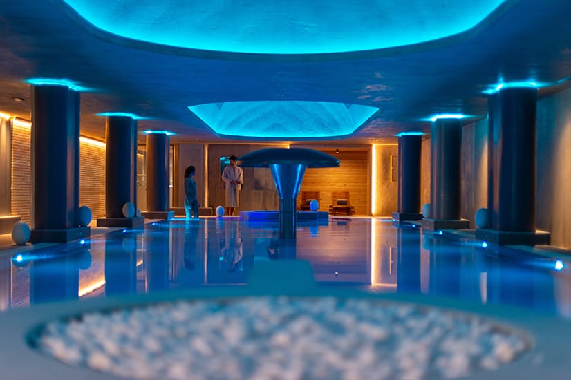 a large room with a pool and a large blue umbrella
