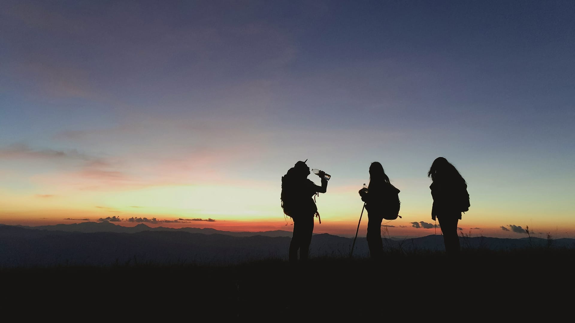 a group of people standing in front of a sunset