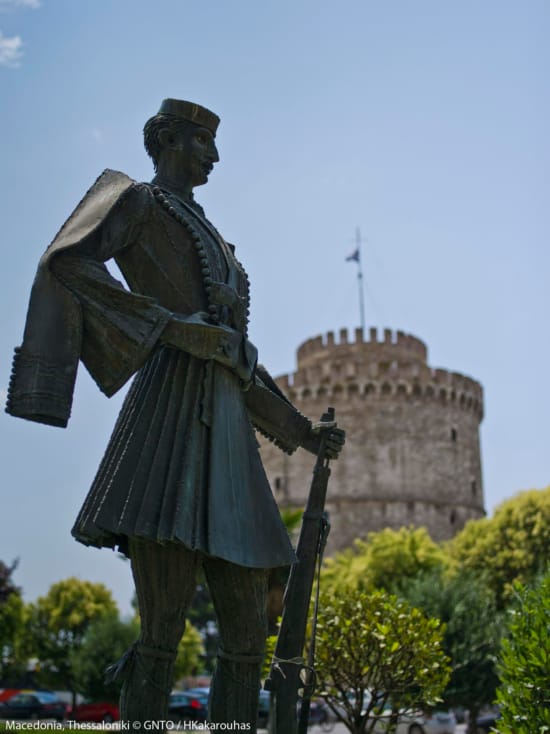 a statue of a person holding a cane in front of a large building