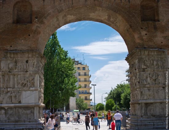 a group of people walking under a large archway