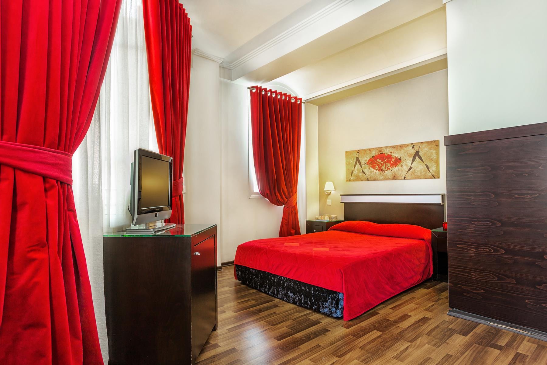 a bedroom with a red bed and a television