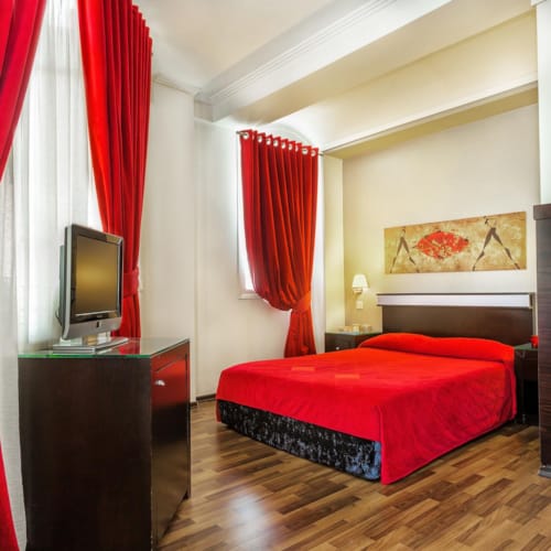 a bedroom with a red bed and a television