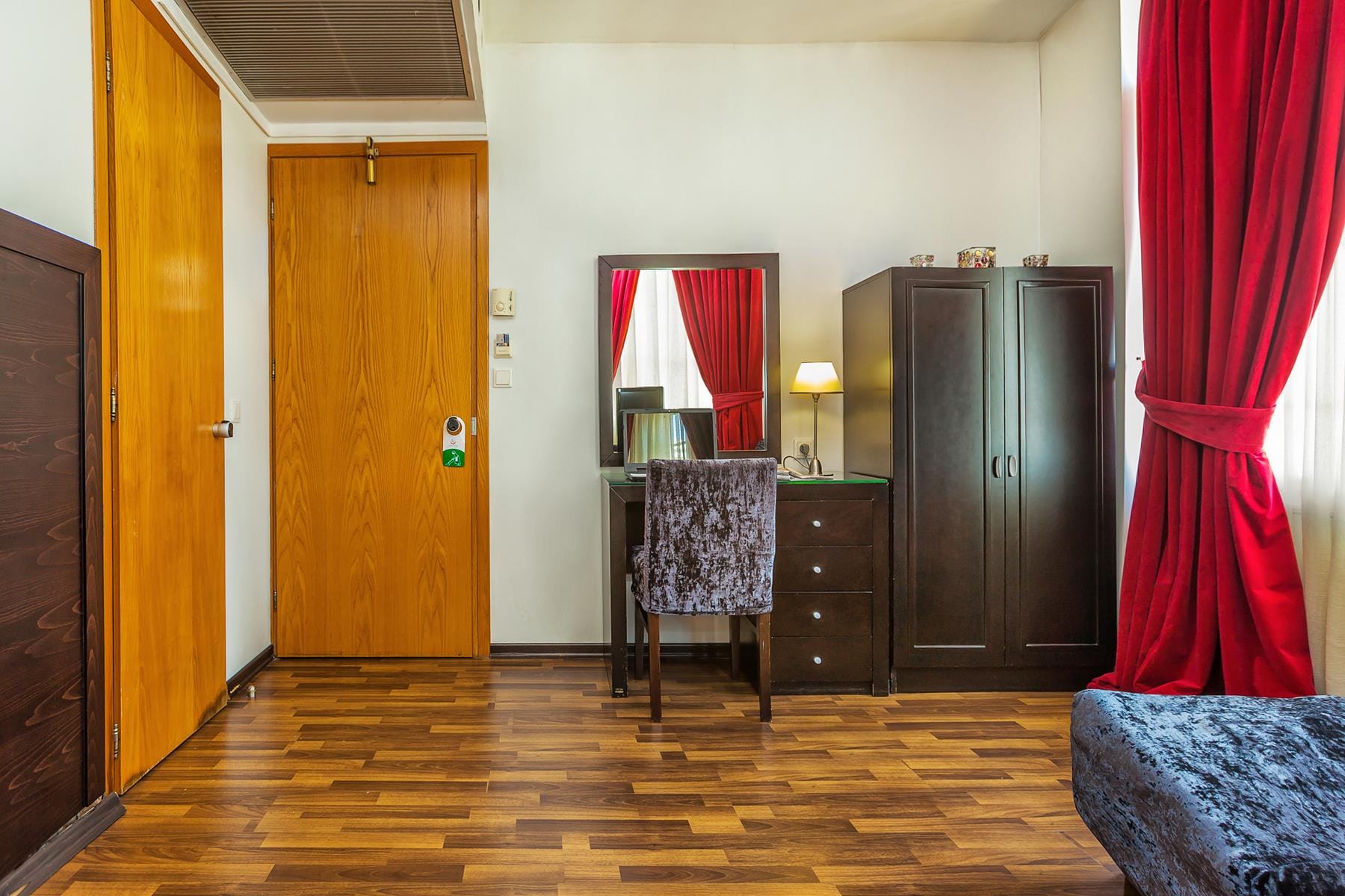 a room with a wood floor and a wood floor with a black cabinet and a red curtain