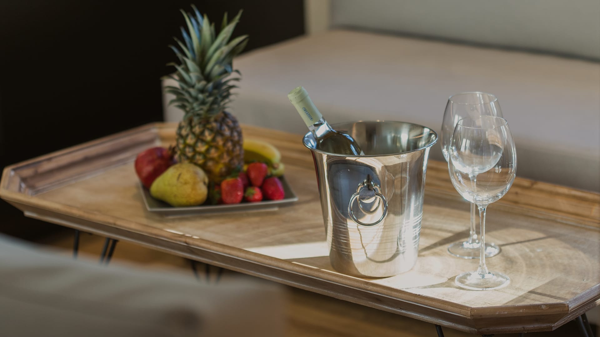 a table with a bowl of fruit and glasses on it