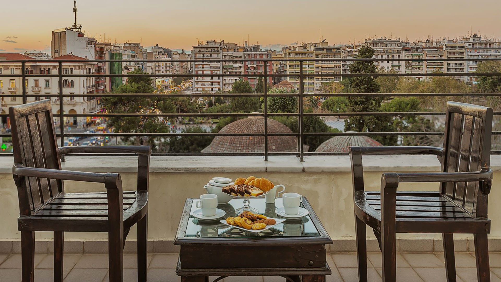 a table with food and drinks on it on a balcony overlooking a city