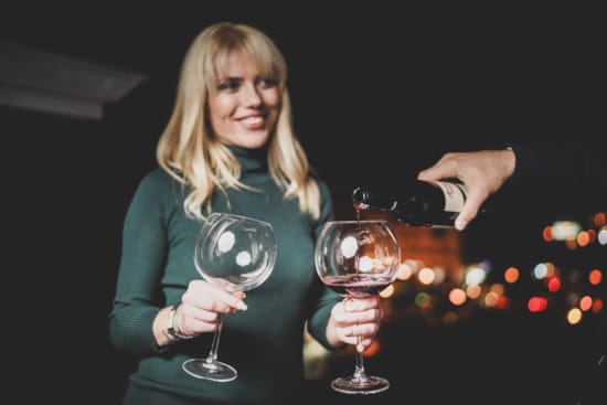 a person pouring wine into glasses